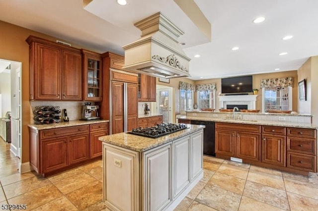 kitchen featuring dishwasher, sink, stainless steel gas cooktop, light stone counters, and a kitchen island