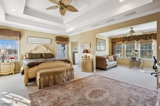 bedroom with a raised ceiling, multiple windows, light carpet, and crown molding