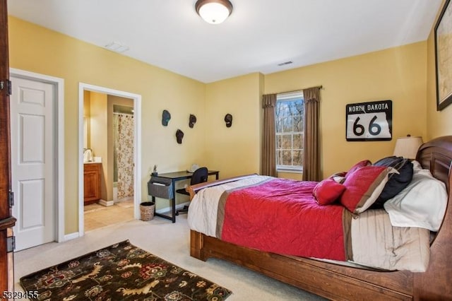 bedroom featuring ensuite bath and light colored carpet