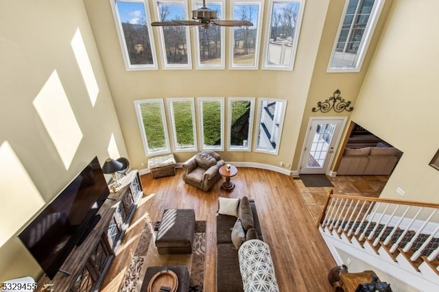 living room with hardwood / wood-style floors, ceiling fan, and a high ceiling