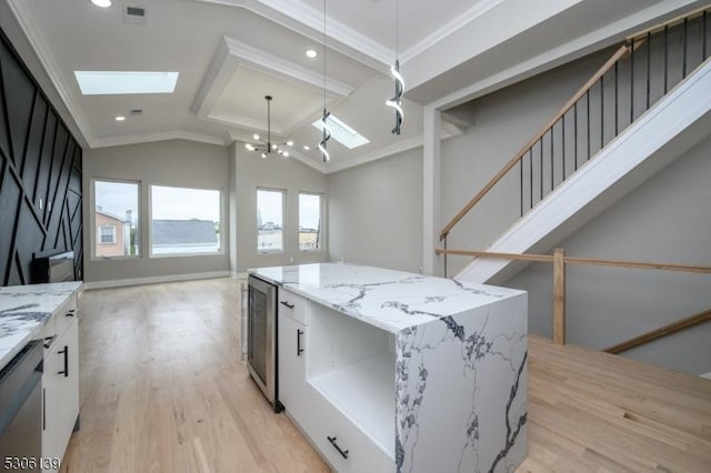 kitchen with light stone countertops, ornamental molding, decorative light fixtures, white cabinets, and a kitchen island