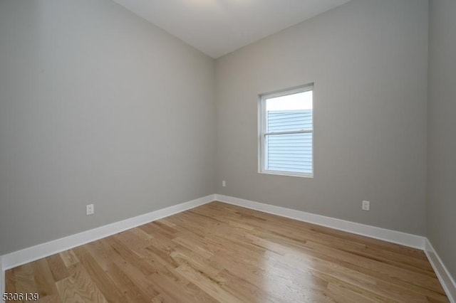 spare room with vaulted ceiling and light hardwood / wood-style flooring