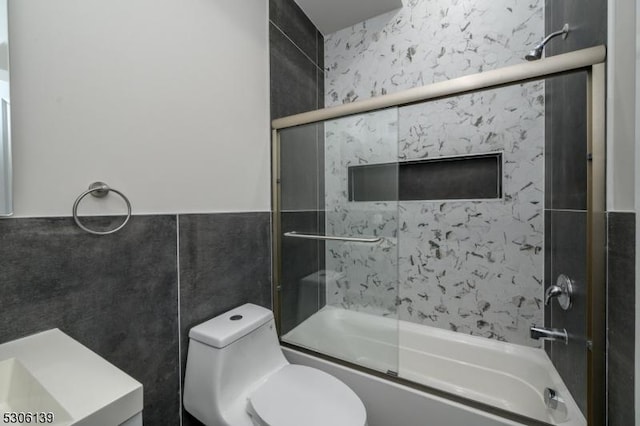 full bathroom featuring vanity, toilet, tile walls, and enclosed tub / shower combo