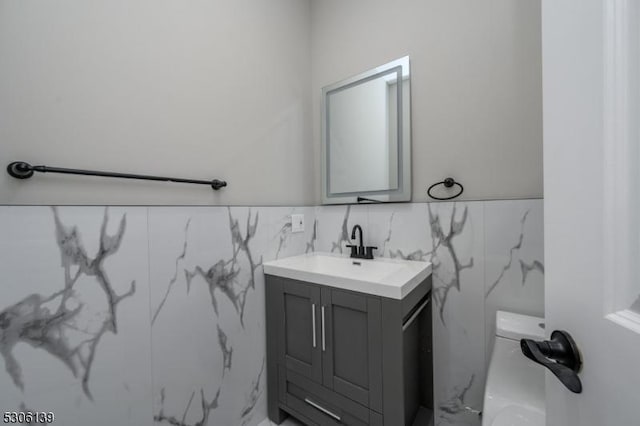 bathroom featuring vanity, toilet, and tile walls