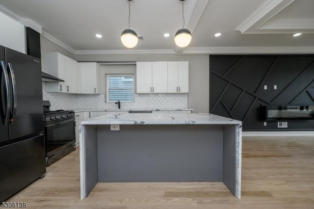 kitchen with a center island, black appliances, light stone countertops, decorative light fixtures, and white cabinetry