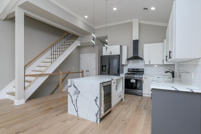 kitchen featuring white cabinetry, wall chimney exhaust hood, stainless steel appliances, pendant lighting, and a kitchen island