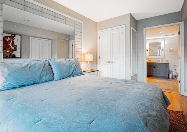 bedroom with ensuite bath, a closet, and light hardwood / wood-style flooring