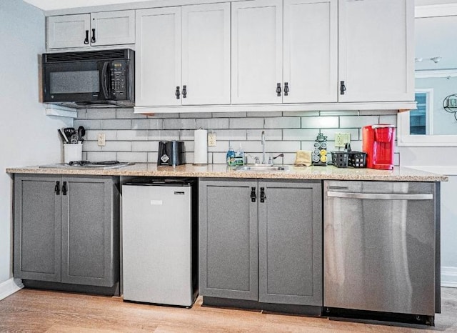 kitchen with sink, gray cabinets, tasteful backsplash, light hardwood / wood-style floors, and stainless steel appliances