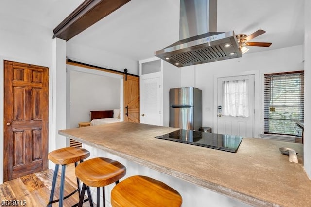413B Lakeside Blvd, Hopatcong Boro, NJ 07843 - kitchen with freestanding refrigerator, wall chimney range hood, black electric stovetop, a barn door, and a ceiling fan