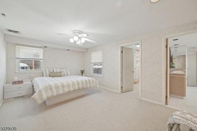 carpeted bedroom with ceiling fan, connected bathroom, and multiple windows