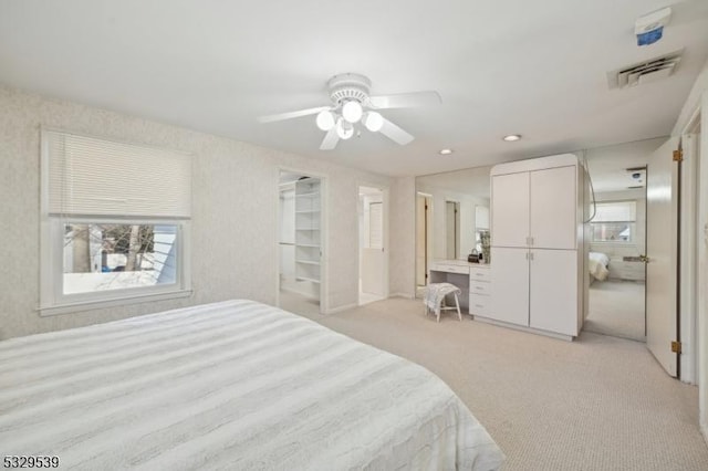 carpeted bedroom featuring ceiling fan, built in desk, and multiple windows