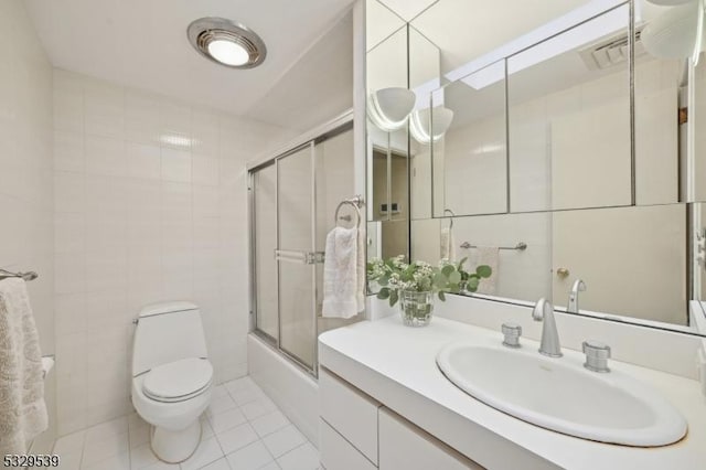 full bathroom with toilet, tile patterned flooring, combined bath / shower with glass door, and tile walls