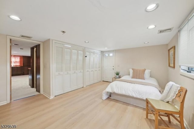 bedroom featuring two closets and light hardwood / wood-style floors