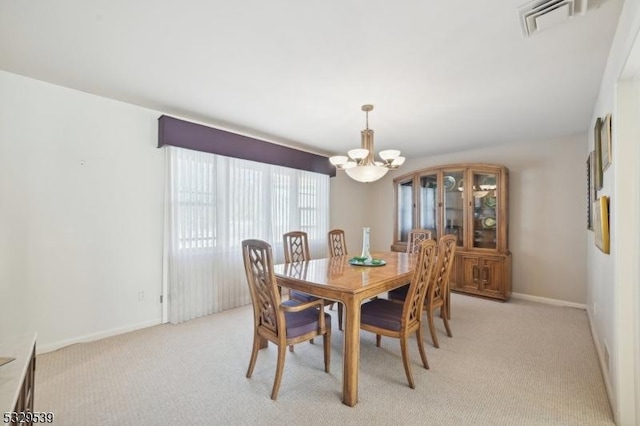 carpeted dining area with a chandelier