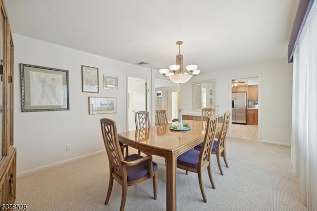 dining space with light colored carpet and an inviting chandelier