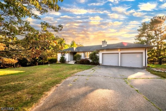 ranch-style home featuring a lawn and a garage