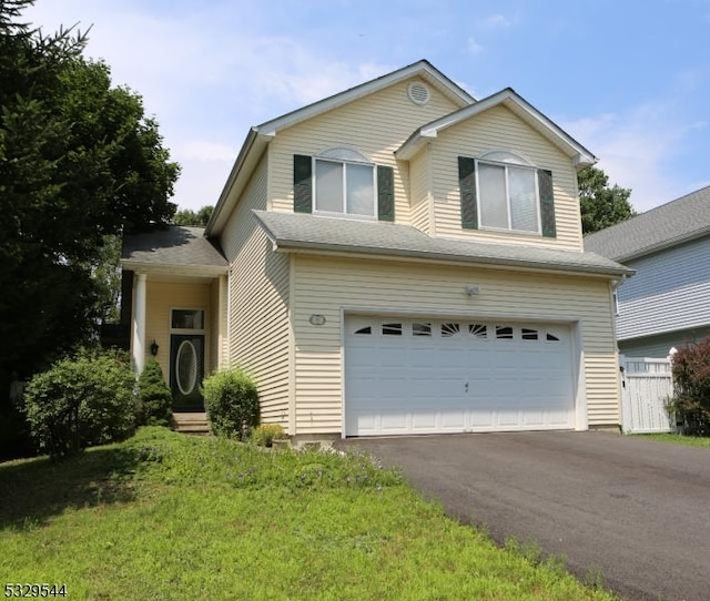 traditional-style house featuring aphalt driveway, fence, and a garage