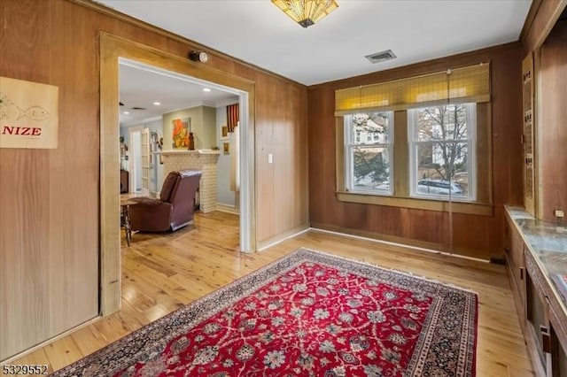 interior space featuring crown molding, wooden walls, and light hardwood / wood-style floors