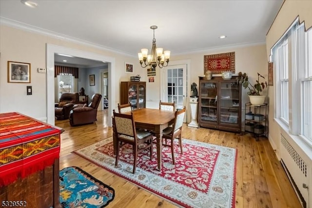 dining room featuring radiator, ornamental molding, and light wood-type flooring