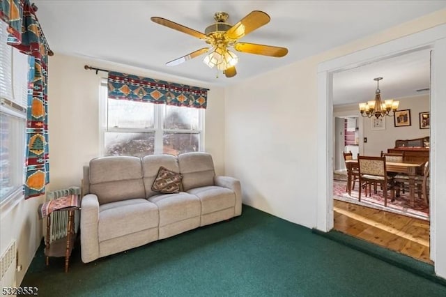 carpeted living room featuring ceiling fan with notable chandelier