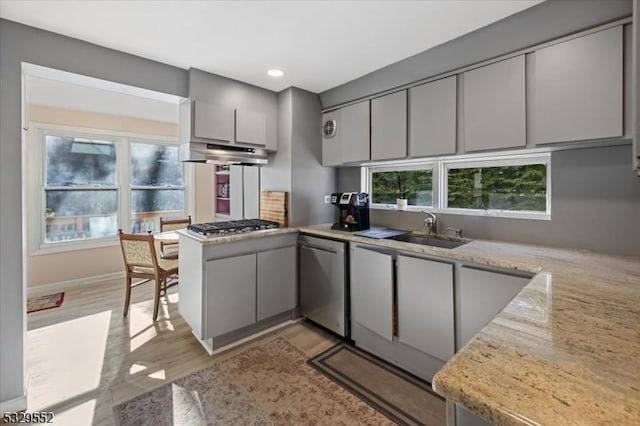 kitchen featuring sink, gray cabinetry, light stone counters, appliances with stainless steel finishes, and kitchen peninsula