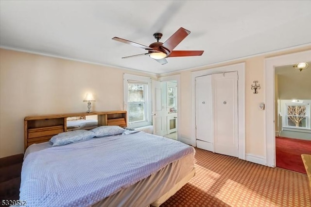 carpeted bedroom with crown molding, ceiling fan, and a closet