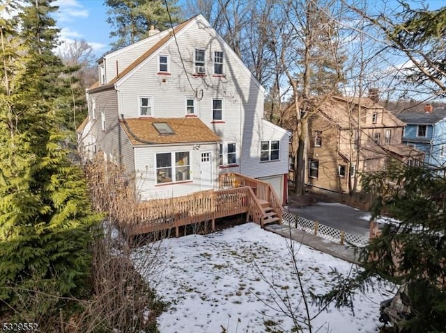 snow covered rear of property featuring a deck