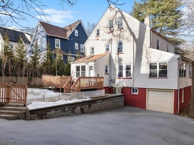 rear view of house featuring a garage and a deck