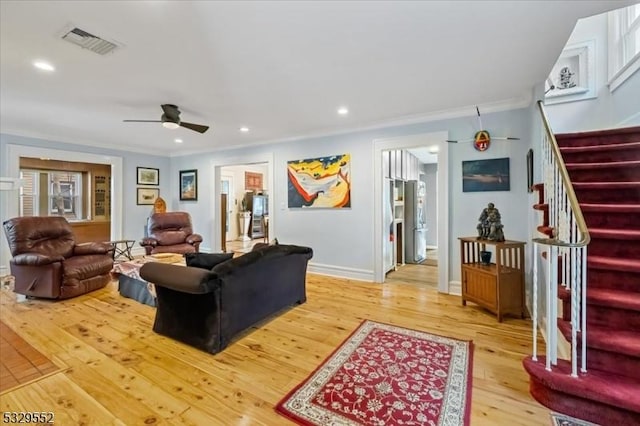 living room with crown molding, ceiling fan, and light hardwood / wood-style floors