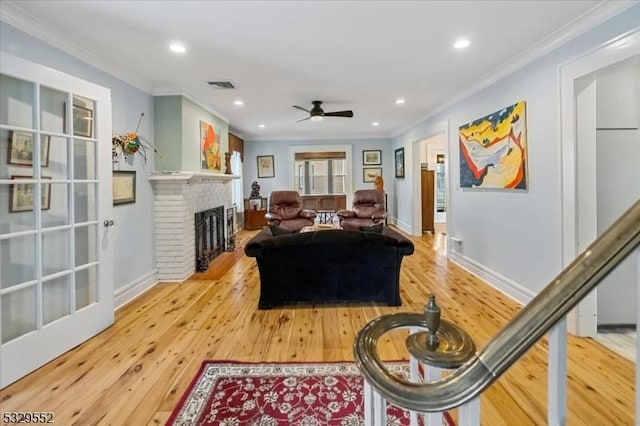 living room featuring crown molding, a brick fireplace, wood-type flooring, and ceiling fan