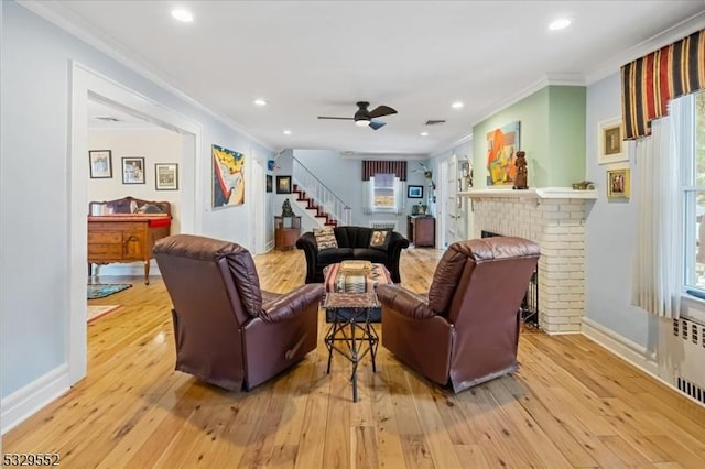 living room with crown molding, ceiling fan, light hardwood / wood-style floors, and a fireplace