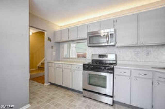 kitchen with tasteful backsplash, appliances with stainless steel finishes, and white cabinets