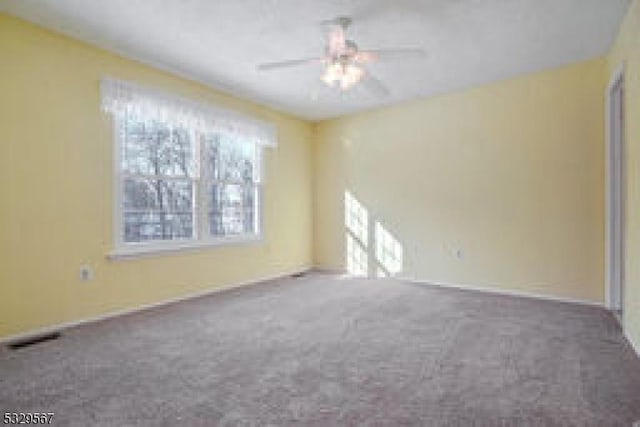 unfurnished room with ceiling fan, carpet flooring, and visible vents