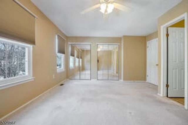 unfurnished bedroom featuring two closets and a ceiling fan