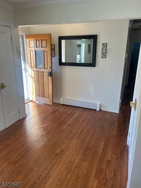 interior space featuring dark hardwood / wood-style floors, ornamental molding, and a baseboard heating unit