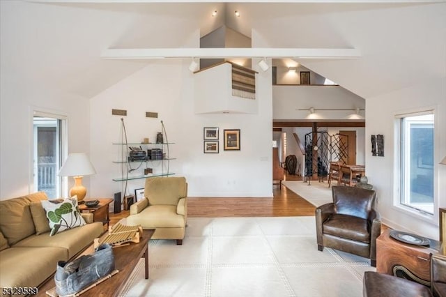 living room featuring vaulted ceiling with beams and light hardwood / wood-style flooring