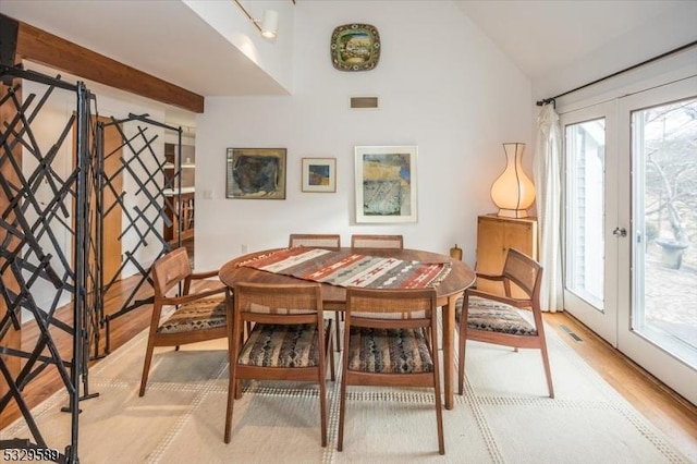 dining area with french doors, vaulted ceiling, light hardwood / wood-style flooring, and plenty of natural light