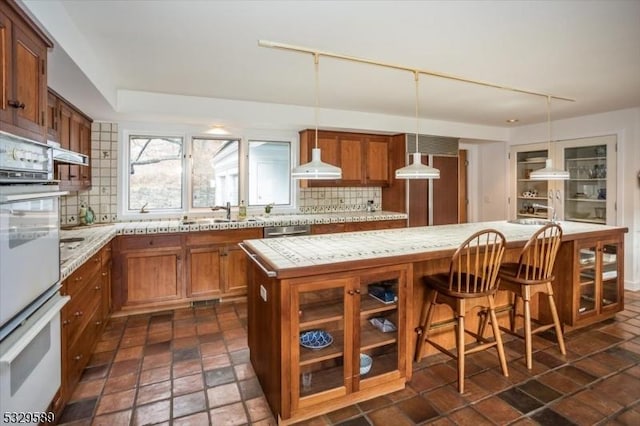 kitchen with a center island, tasteful backsplash, hanging light fixtures, and sink