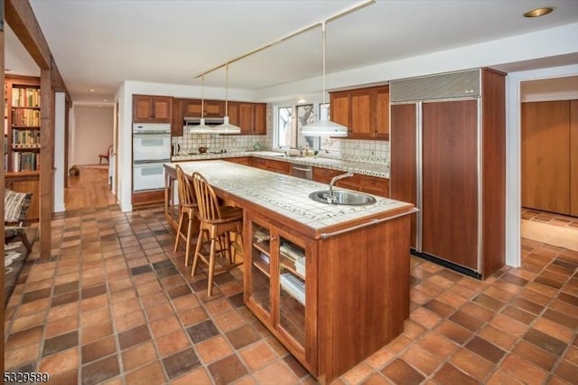 kitchen with decorative light fixtures, paneled built in refrigerator, a kitchen island, and decorative backsplash