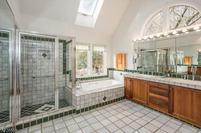 bathroom featuring tile patterned flooring, vanity, lofted ceiling with skylight, and separate shower and tub