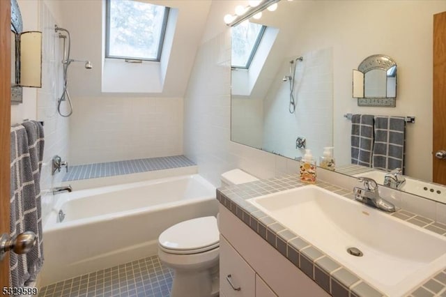 bathroom featuring vanity, vaulted ceiling with skylight, tile patterned flooring, toilet, and a tub to relax in