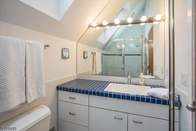 bathroom featuring vanity, toilet, and vaulted ceiling with skylight