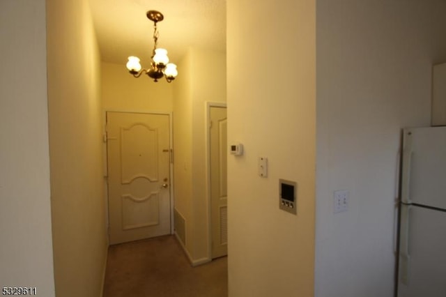 hallway featuring carpet floors and an inviting chandelier