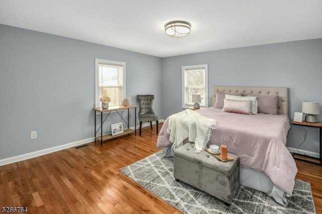 bedroom with multiple windows and hardwood / wood-style flooring