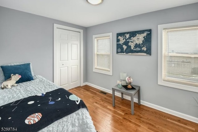 bedroom with hardwood / wood-style floors, a closet, and multiple windows