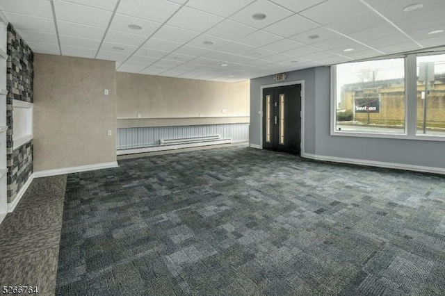 unfurnished living room with a drop ceiling and dark carpet