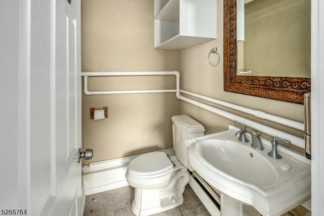 bathroom with baseboard heating, toilet, tile patterned flooring, and sink