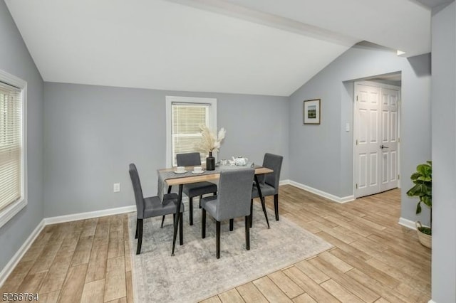 dining area with a healthy amount of sunlight, lofted ceiling, and light wood-type flooring