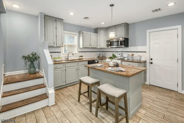 kitchen with a kitchen breakfast bar, decorative backsplash, sink, and light hardwood / wood-style floors