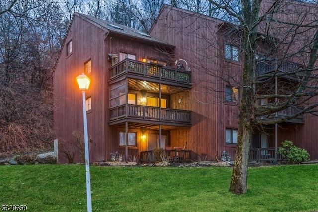 rear view of property with a yard and a balcony